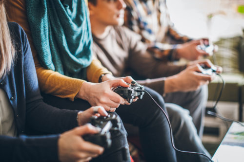 A group of friends holding gaming controls while sitting on a couch